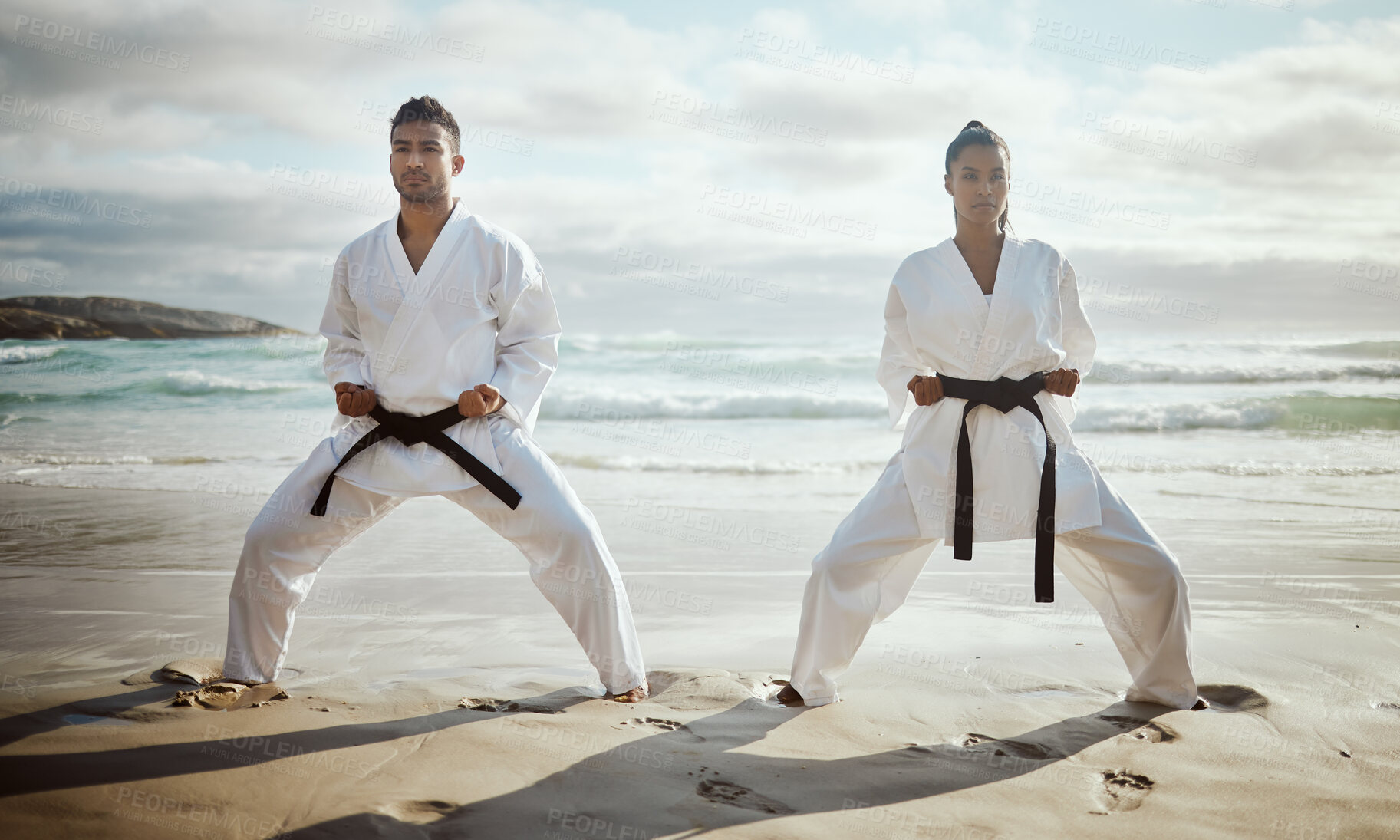 Buy stock photo Full length shot of two young martial artists practicing karate on the beach