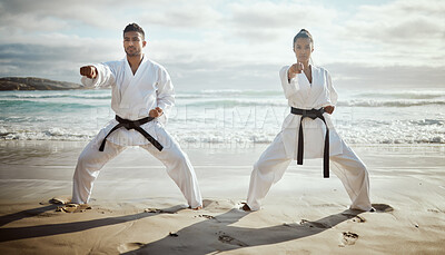 Buy stock photo Full length shot of two young martial artists practicing karate on the beach