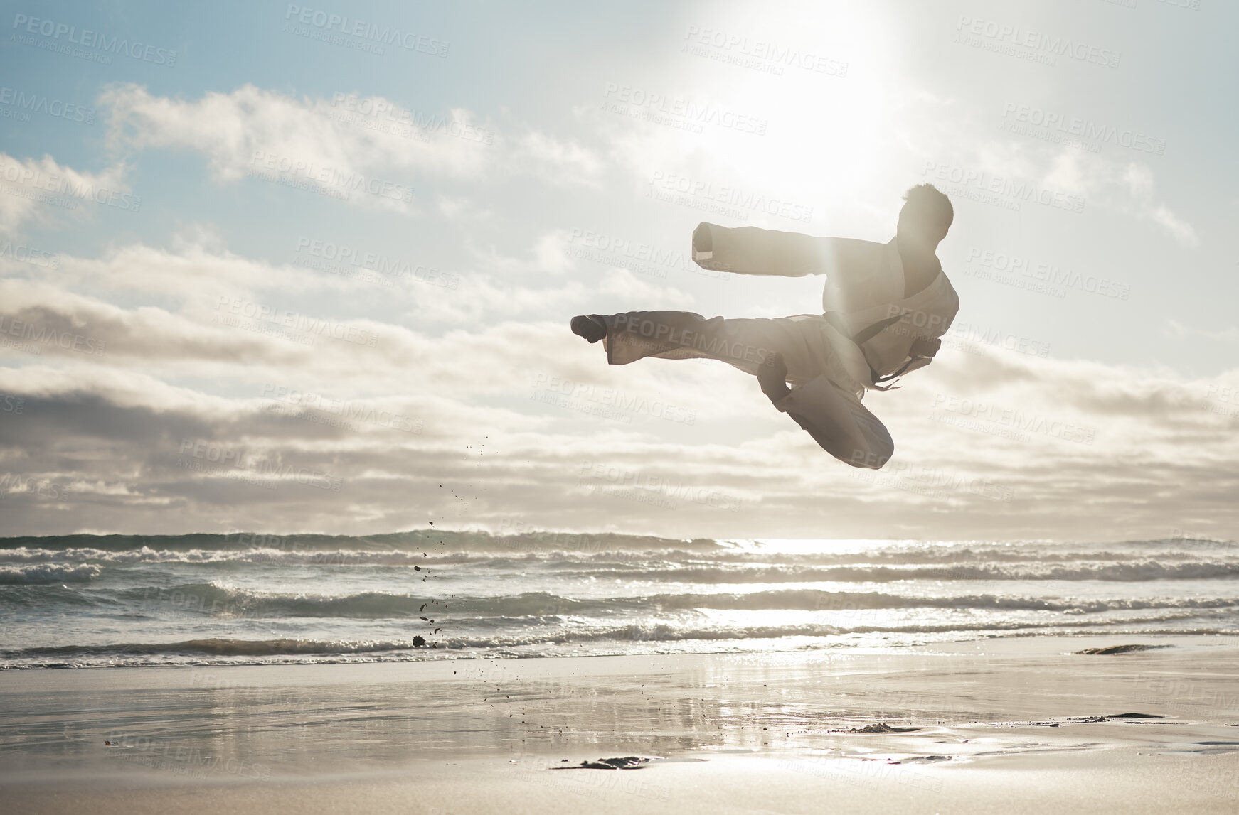 Buy stock photo Beach, karate and man with training, kick and fitness with achievement, jump and practice. Active, routine and ocean with guy, lens flare and talent with exercise, hobby and martial arts for wellness