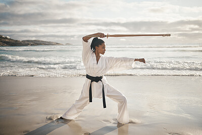 Buy stock photo Full length shot of an attractove young female martial artist practicing karate on the beach