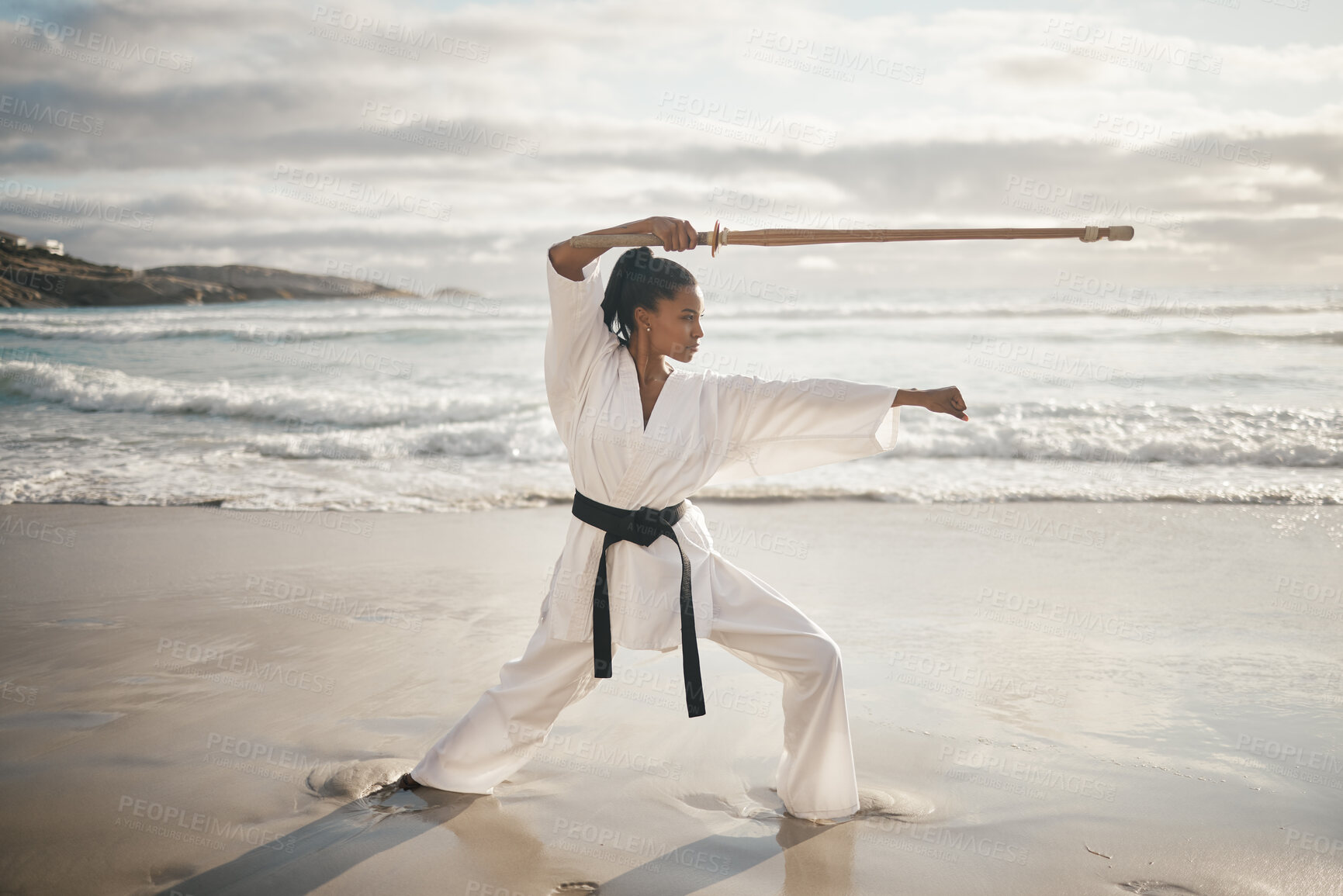 Buy stock photo Black woman, stick and beach for karate training, fitness and samurai or master fighter in outdoor. Female person, exercise and warrior for martial arts in nature, ocean and workout self defence