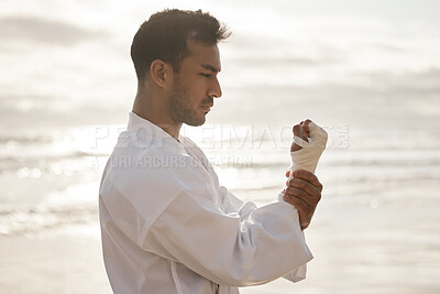 Buy stock photo Cropped shot of a handsome young male martial artist practicing karate on the beach