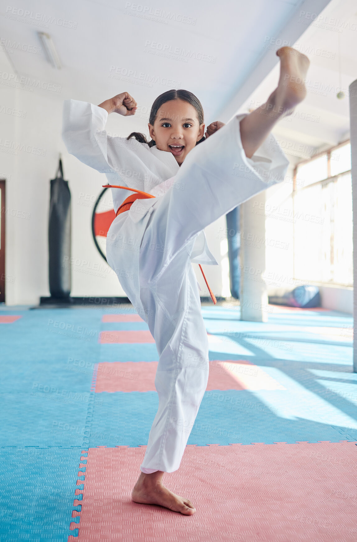 Buy stock photo Martial arts, kick and girl in studio for fitness, training and fight with orange belt, development and energy. Student, kung fu and portrait in dojo as workout for self defense, karate and taekwondo