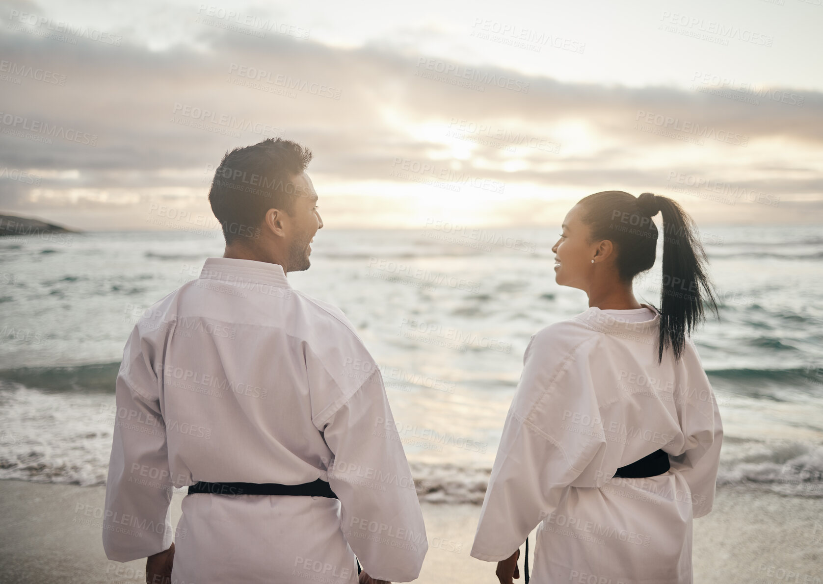 Buy stock photo Rearview shot of two young martial artists practicing karate on the beach