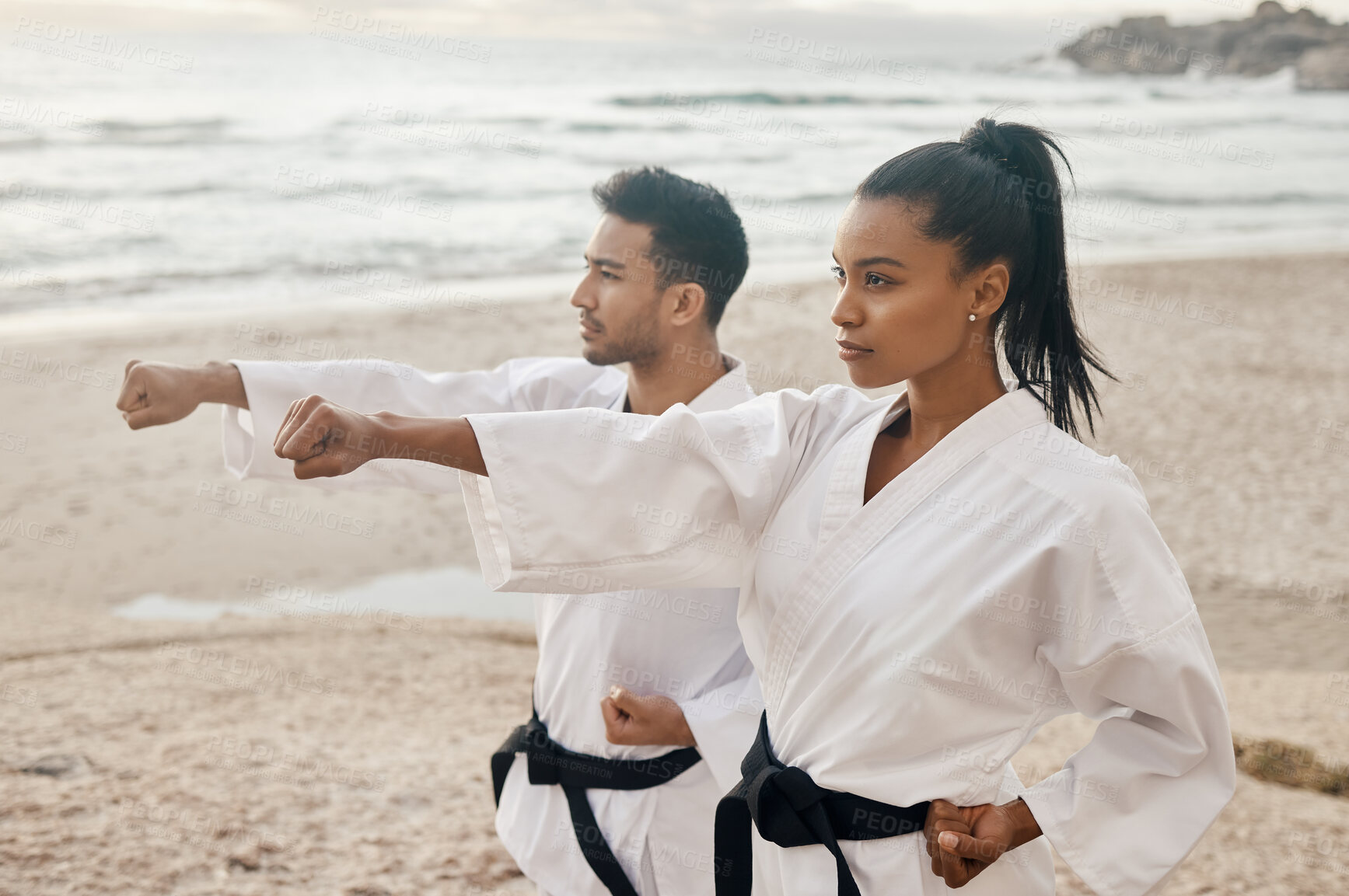 Buy stock photo People, karate and beach with kata for martial arts, training or self defense in nature. Man and woman with fist in stance or movement on rock by ocean coast for taekwondo, discipline or recreation