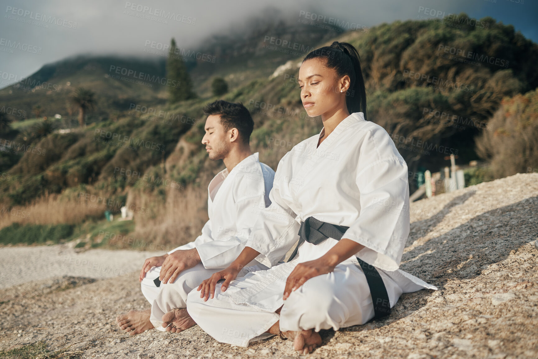 Buy stock photo Calm people, karate and beach with meditation for martial arts, training or self defense in nature. Man and woman in zen, spiritual or awareness on rock by ocean coast for taekwondo or discipline