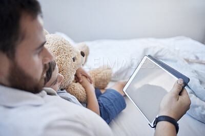 Buy stock photo Shot of a young father using a digital tablet with his son at home
