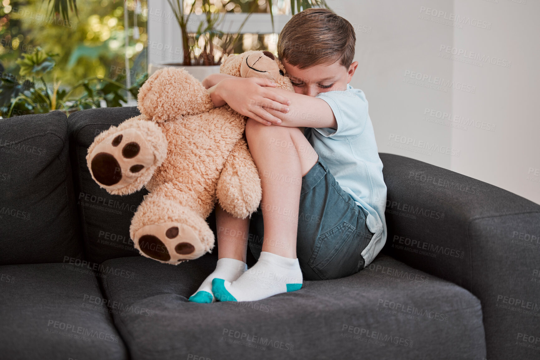 Buy stock photo Sad, child and sofa with teddy bear at house for discipline conflict, family crisis and bullying trauma in living room. Boy, fear and support of toy for mental health, anxiety and domestic violence