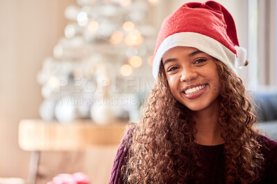 Buy stock photo Shot of a young woman wearing a Christmas hat while sitting at home