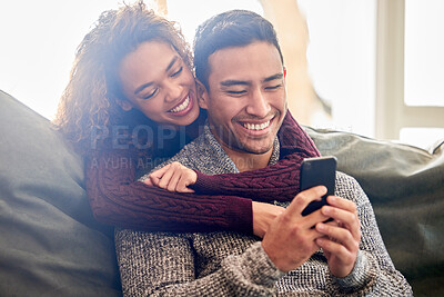 Buy stock photo Happy couple, phone and hug on couch with internet meme, reading news or online streaming service at home. Young interracial woman and man or partner on funny website, connection and love on sofa