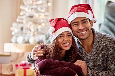 Buy stock photo Shot of a young couple wearing Christmas hats while sitting at home