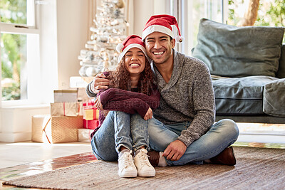Buy stock photo Shot of a young couple wearing Christmas hats while sitting at home