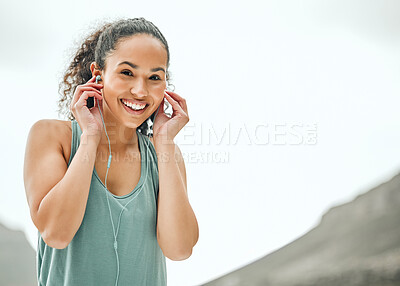 Buy stock photo Shot of a young woman listening to music while on a run