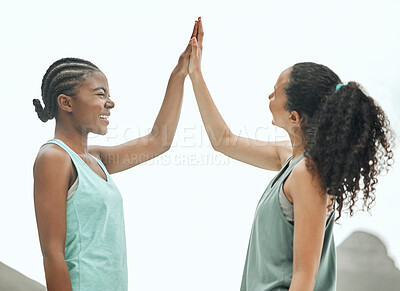 Buy stock photo Shot of two young women giving each other a high five while working out in nature