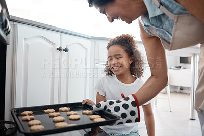 Buy stock photo Shot of a mature woman inserting a tray of cookies she baked with her granddaughter into an oven