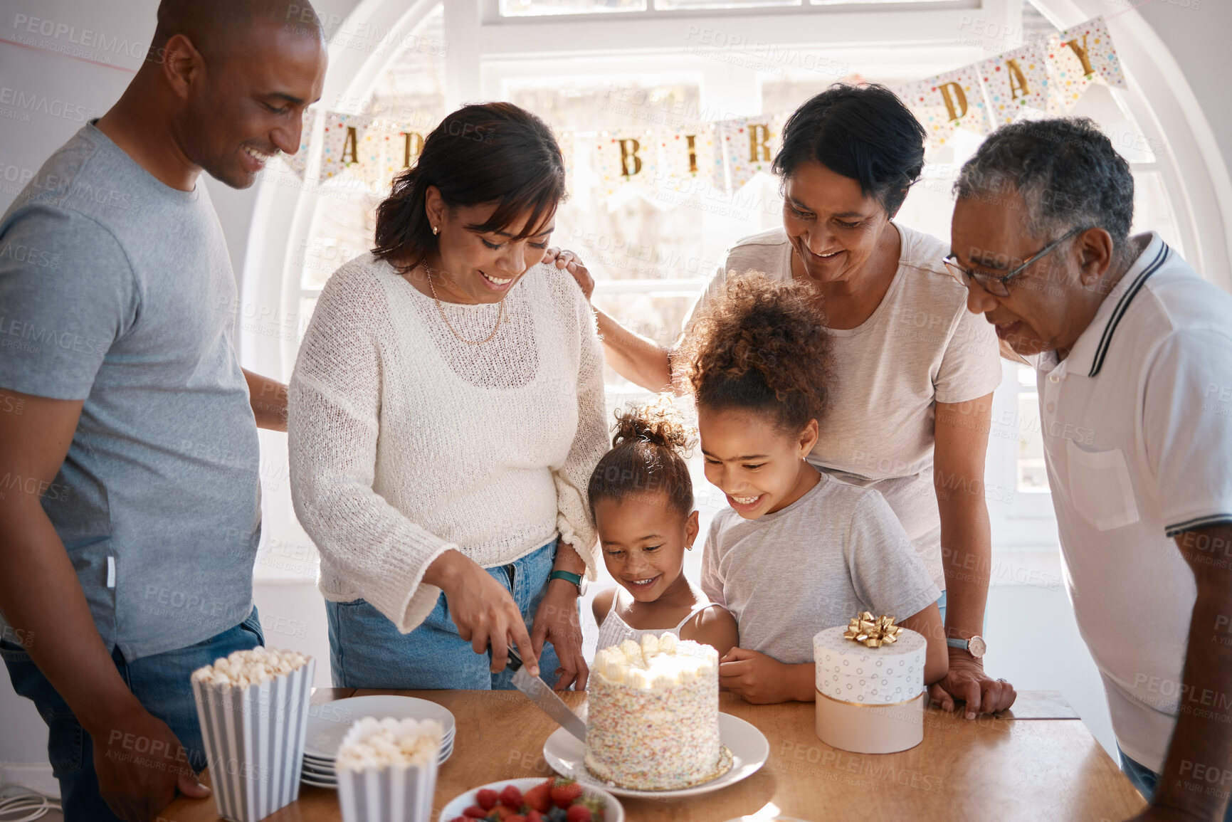 Buy stock photo Shot of a family cutting a cake and  celebrating a birthday party at home