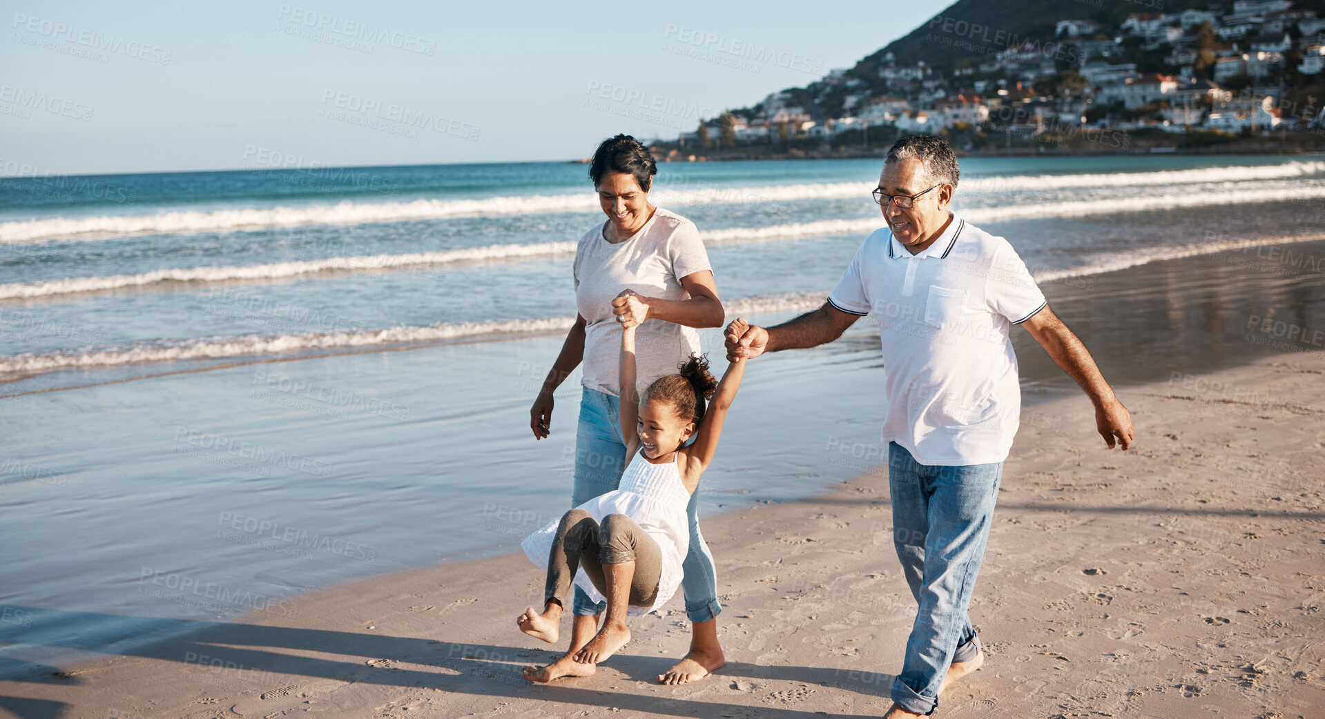 Buy stock photo Shot of a little girl spending time with her grandparents at the beach
