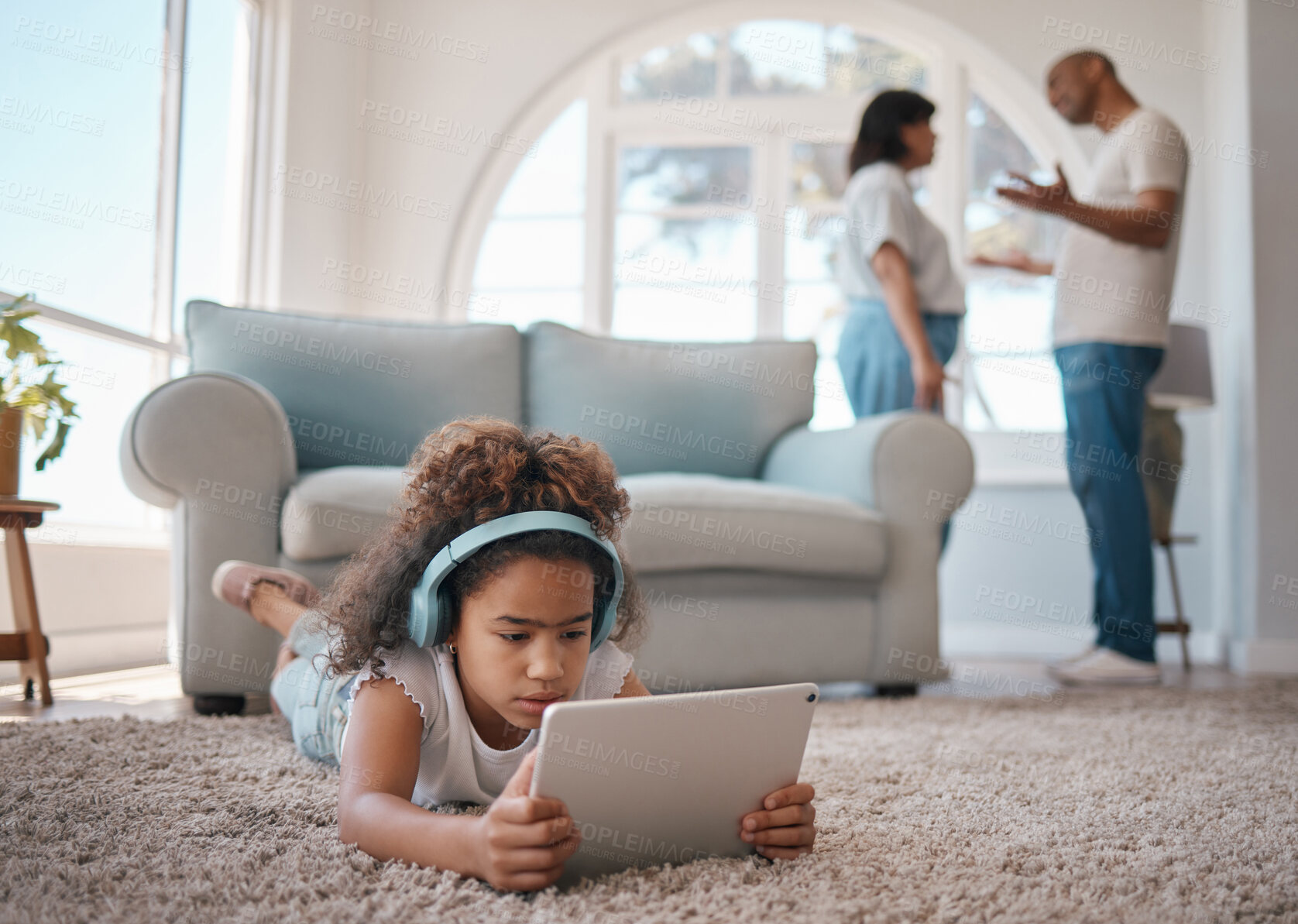 Buy stock photo Shot of a young girl using a digital tablet while her parents argue
