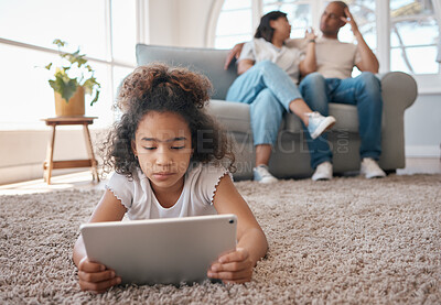 Buy stock photo Shot of a little girl using a digital tablet while her parents relax