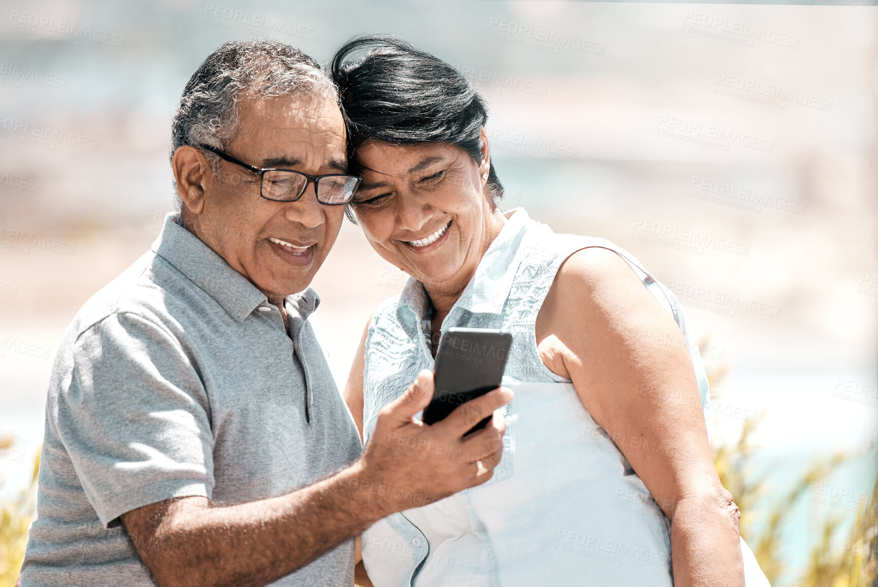 Buy stock photo Shot of a senior couple using a phone in nature