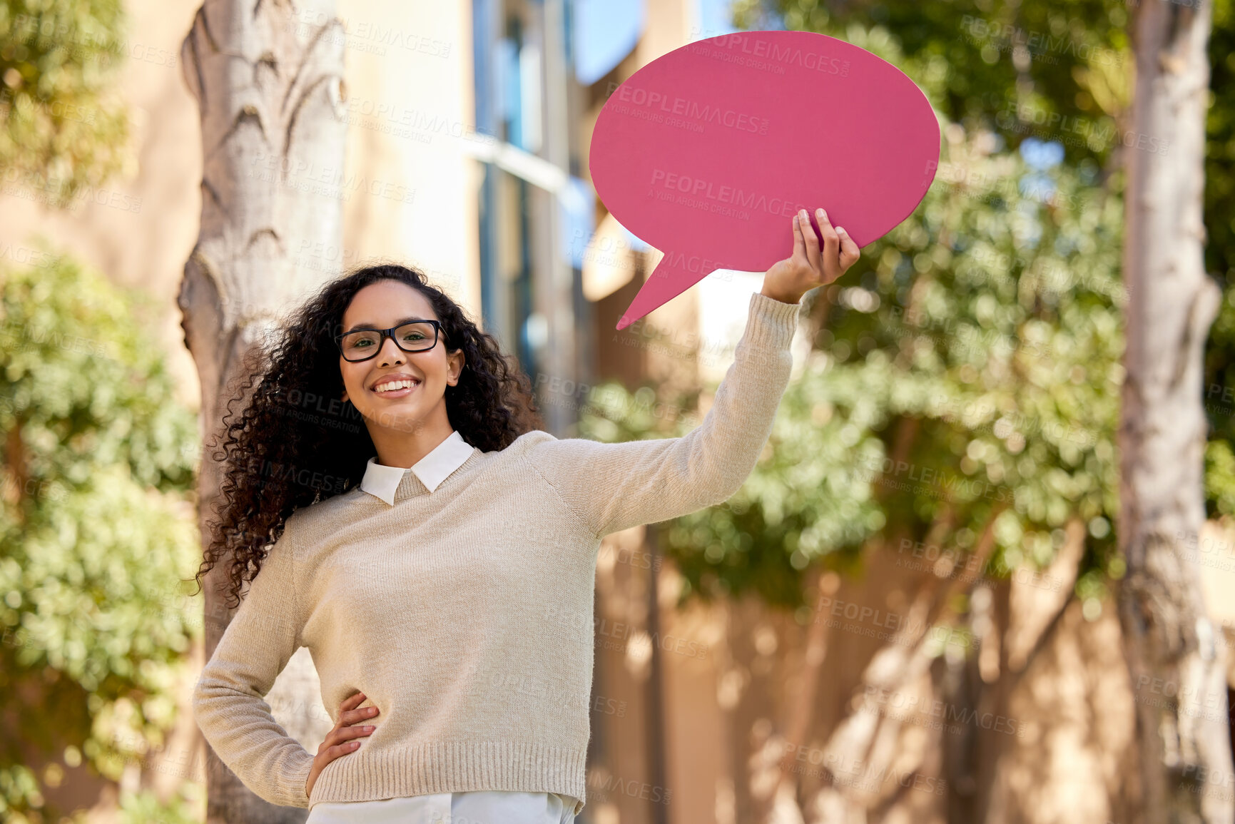 Buy stock photo Shot of a beautiful young student holding a speech bubble above her head while standing outside