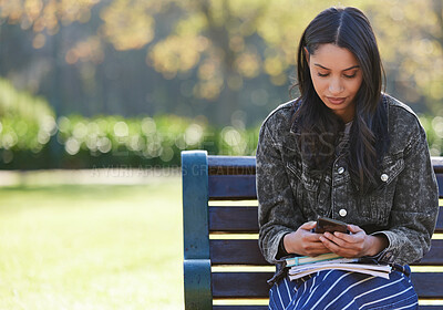 Buy stock photo Shot of a beautiful young student using her phone while sitting outside