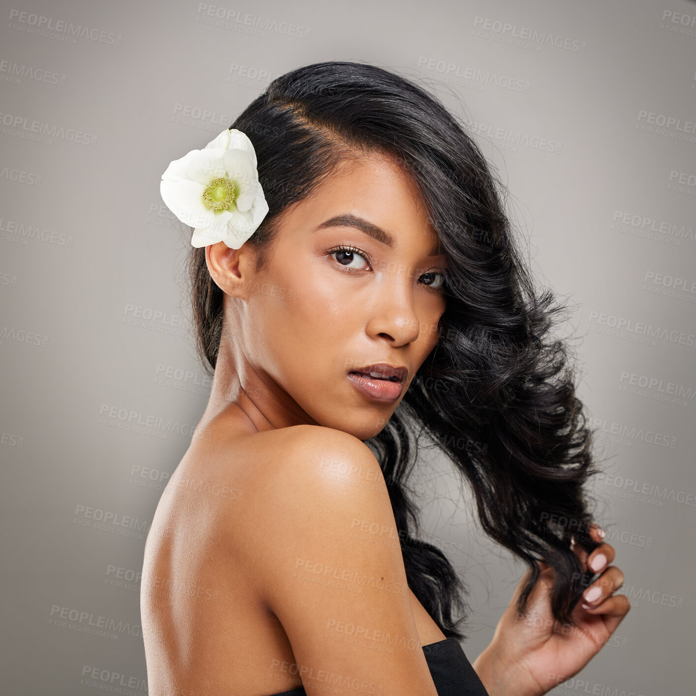 Buy stock photo Portrait, hair care and girl in studio with flower for cosmetics, treatment and shine on grey background. Woman, floral art or curly style for female model with volume, texture or keratin results
