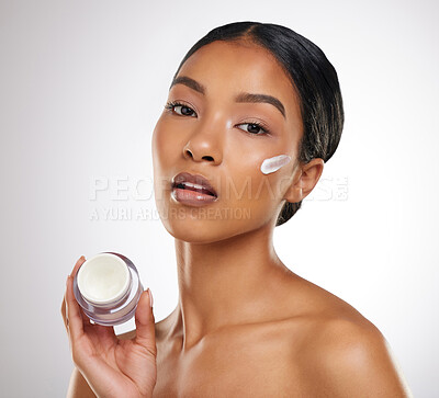 Buy stock photo Studio portrait of an attractive young woman posing with a container of face lotion against a grey background