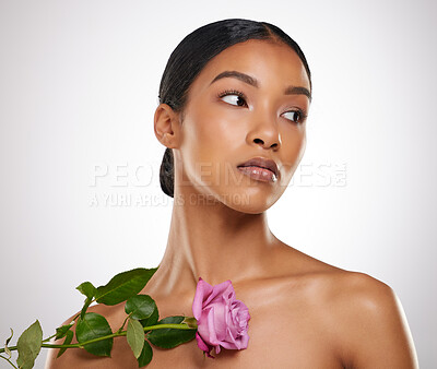 Buy stock photo Studio shot of an attractive young woman posing with a pink rose against a grey background
