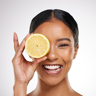 Buy stock photo Studio portrait of an attractive young woman posing with half a lemon against a grey background