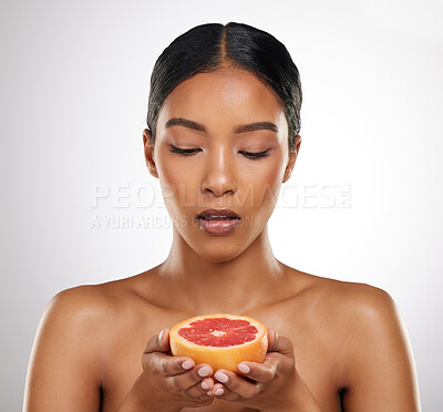 Buy stock photo Studio shot of an attractive young woman posing with half a grapefrut against a grey background