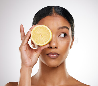 Buy stock photo Studio shot of an attractive young woman posing with half a lemon against a grey background