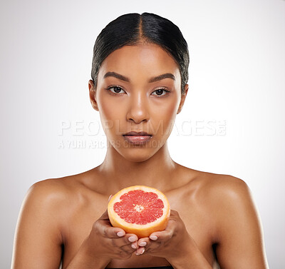 Buy stock photo Studio portrait of an attractive young woman posing with half a grapefrut against a grey background