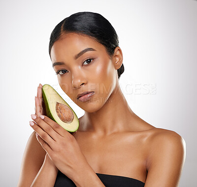 Buy stock photo Studio portrait of an attractive young woman posing with half an avocado against a grey background