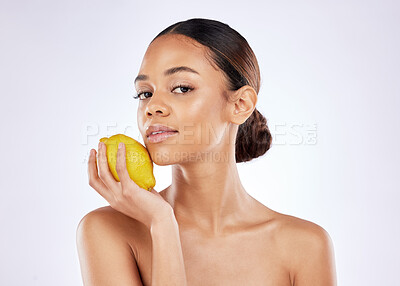Buy stock photo Shot of a beautiful young woman posing holding a lemon against a studio background