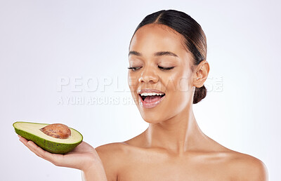 Buy stock photo Shot of a beautiful young woman posing with an avocado against a studio background