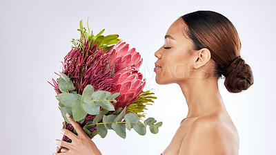 Buy stock photo Shot of a young woman smelling a bouquet of flowers against a studio background