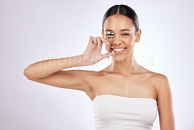 Buy stock photo Shot of a young woman curling her eyelashes against a studio background