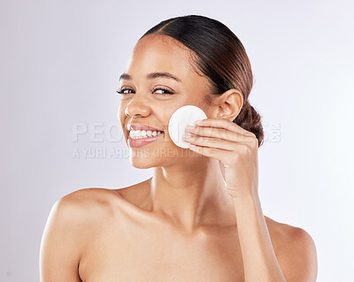 Buy stock photo Shot of a young woman applying skincare using a cotton pad against a studio background