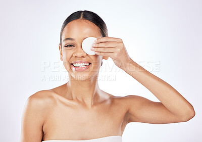 Buy stock photo Shot of a beautiful young woman covering her eye with a cotton pad against a studio background