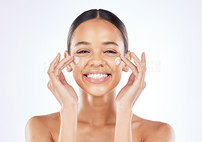 Buy stock photo Shot of a young woman applying moisturiser to her face against a studio background