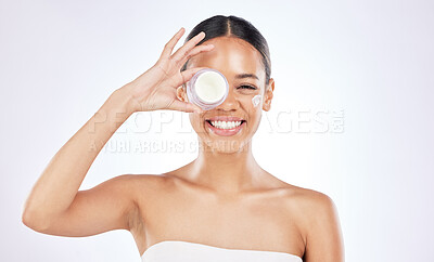 Buy stock photo Shot of a happy young woman holding a pot of moisturiser against a studio background