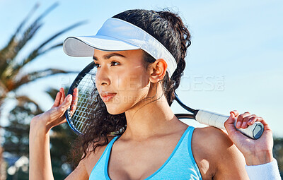Buy stock photo Shot of an attractive young woman standing and holding a tennis racket while looking contemplative during practice