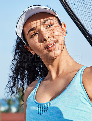 Buy stock photo Shot of an attractive young woman standing and holding a tennis racket while looking contemplative during practice