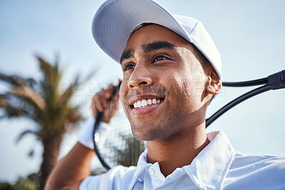 Buy stock photo Shot of a handsome young man standing and holding a tennis racket during practice
