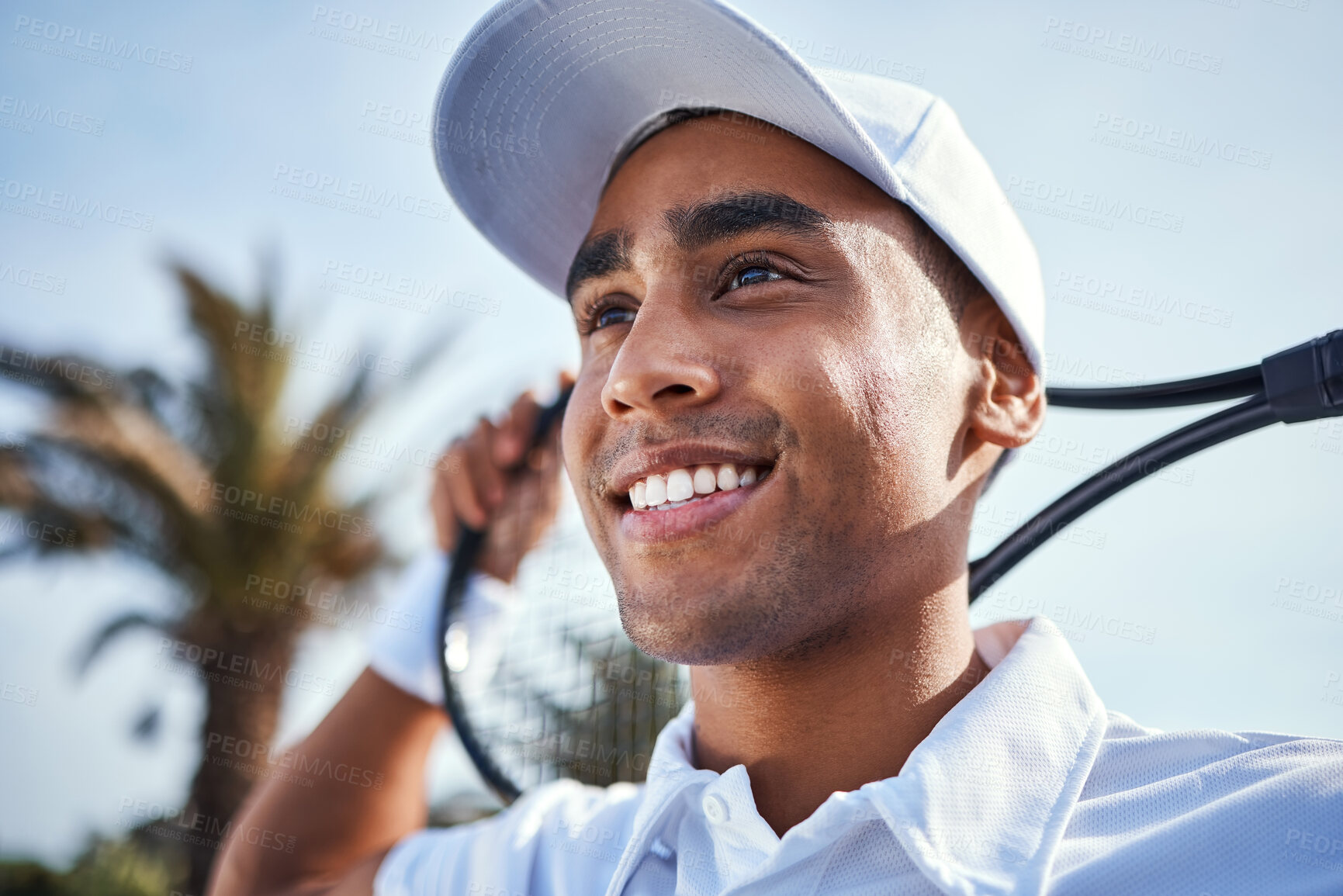 Buy stock photo Shot of a handsome young man standing and holding a tennis racket during practice