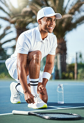 Buy stock photo Full length shot of a handsome young man kneeling down to tie his shoelaces before tennis practice