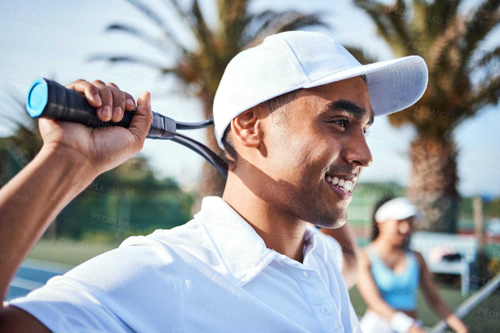 Buy stock photo Shot of a handsome young man standing and holding a tennis racket during practice