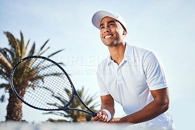Buy stock photo Shot of a handsome young man standing alone and holding a tennis racket during a game of tennis