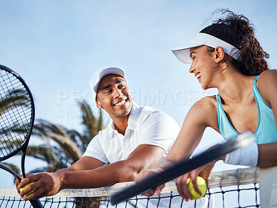 Buy stock photo Shot of two tennis players standing together and leaning on the net during practice